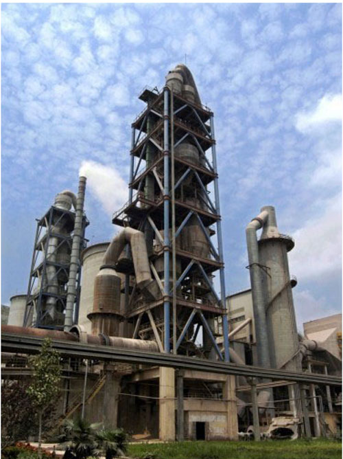 Cement plant with concrete silos and processing towers under blue sky.