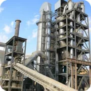 Modern cement plant with vertical preheater towers, rotary kiln, and exhaust stack for clinker production.